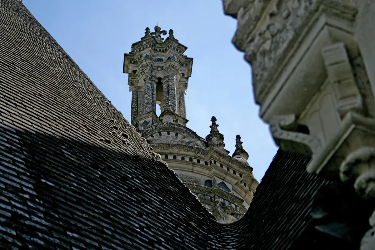 Toit d’ardoise d’un château de la Loire, lanterne de pierre sculptée en arrière-plan