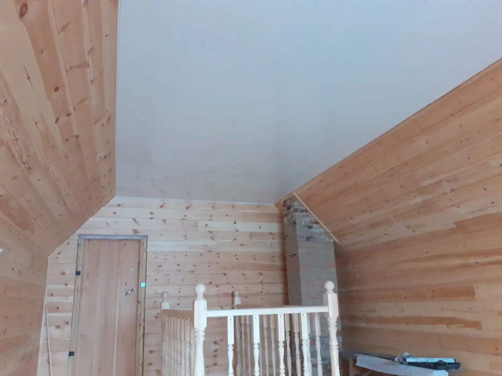 Comble aménagé en lambris de bois clair, rampants et plafond tendu blanc