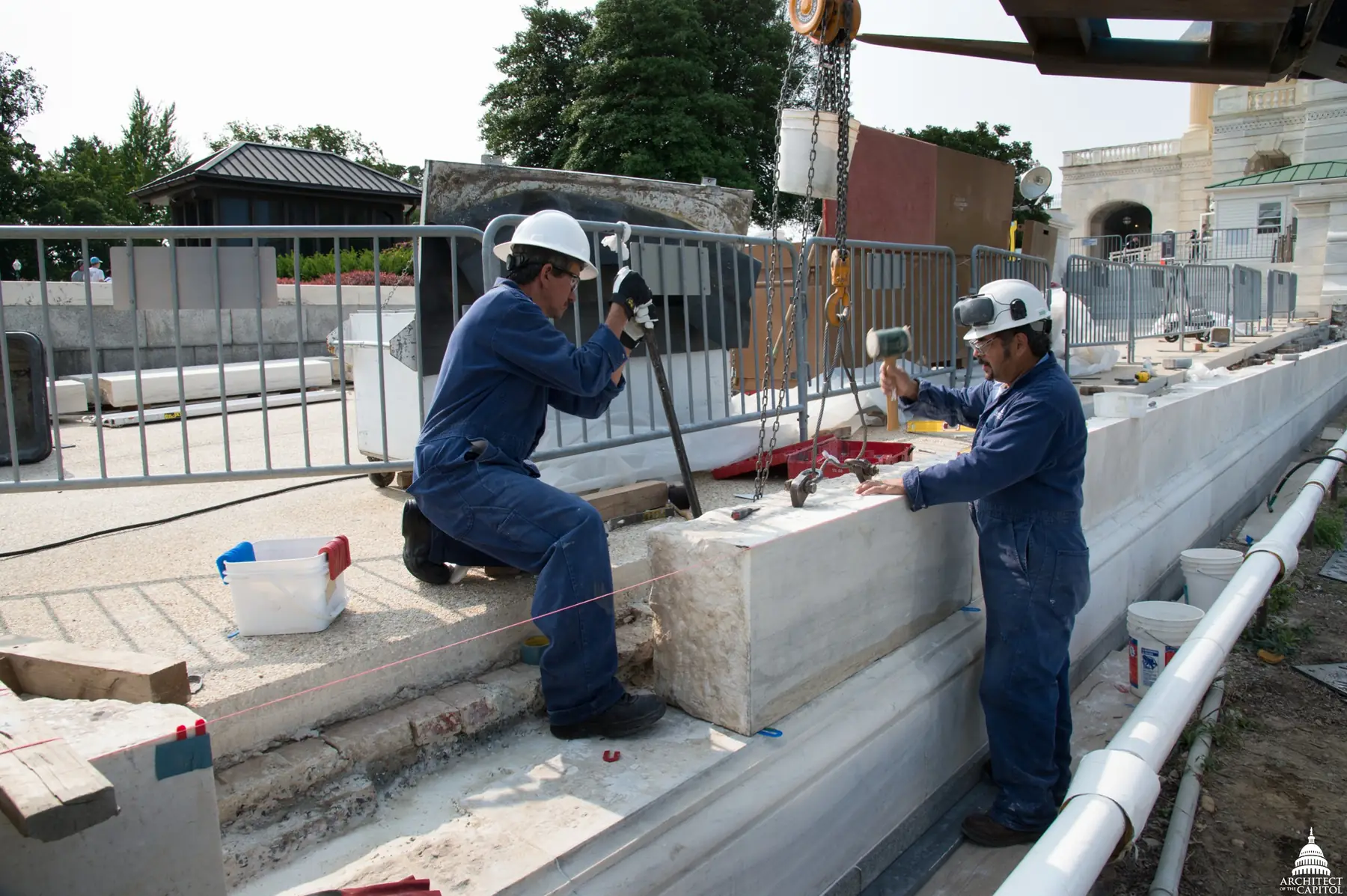 Deux maçons en tenue de chantier reprennent un mur de pierre de taille