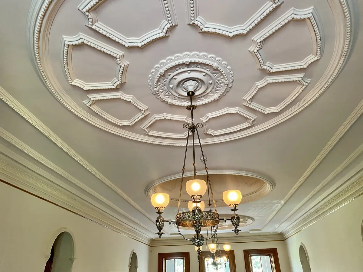 Plafond à moulures et rosace en plâtre, lustre suspendu au centre