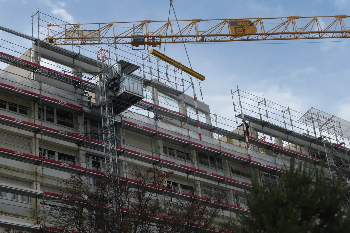 Chantier de surélévation : étage ajouté sous échafaudage, grue au-dessus du toit